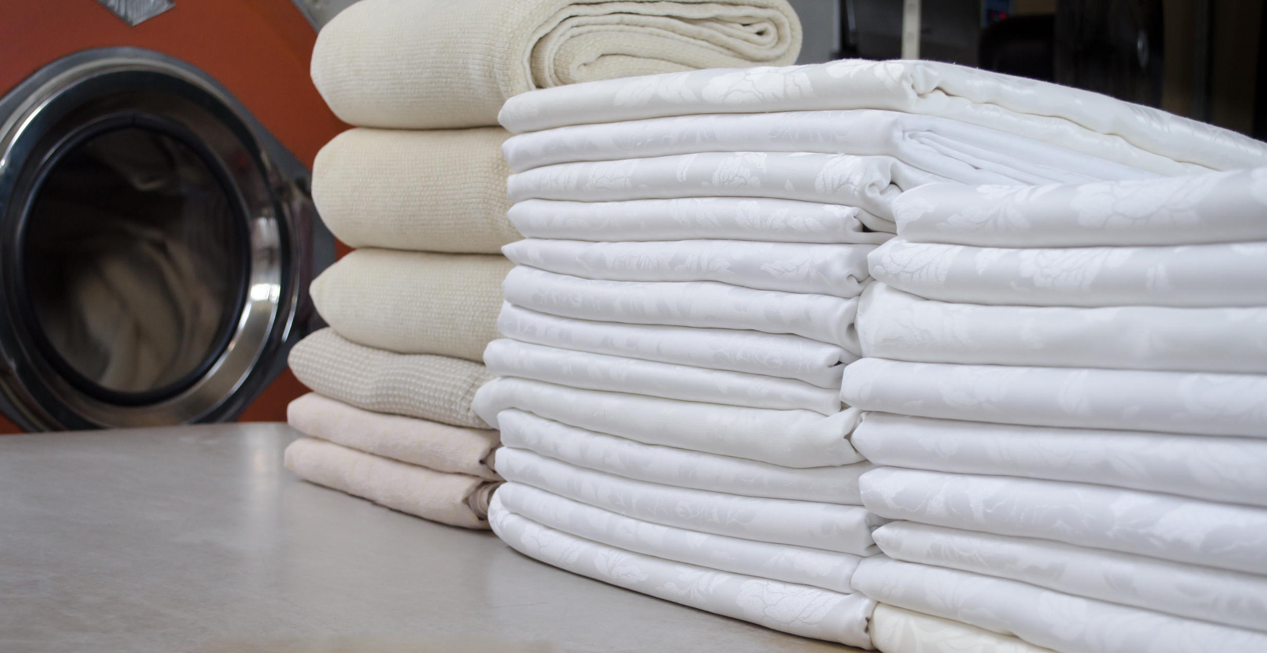 Stack of folded white cloths in an industrial laundry. Cleaning and service concept.